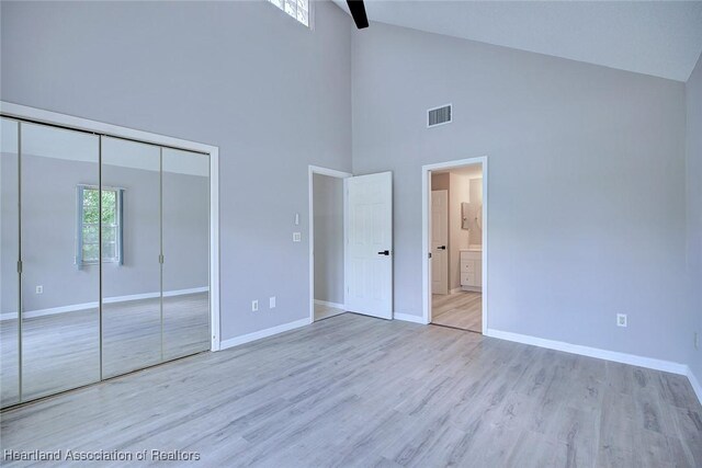 unfurnished bedroom with baseboards, visible vents, a closet, and high vaulted ceiling