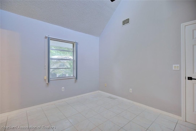 spare room featuring a textured ceiling, visible vents, light tile patterned floors, and vaulted ceiling