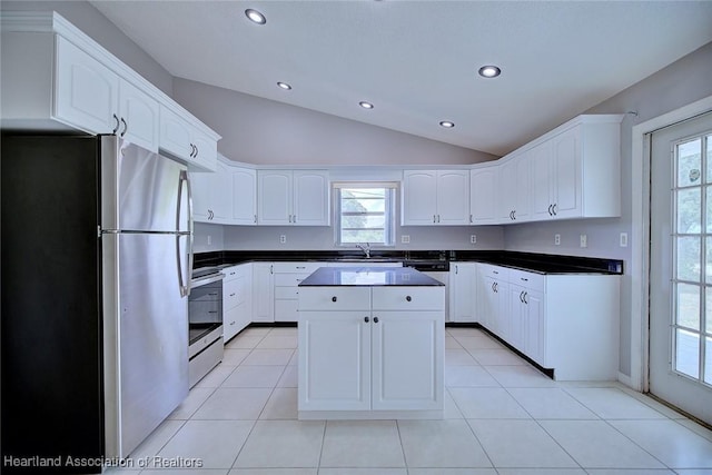 kitchen featuring appliances with stainless steel finishes, a healthy amount of sunlight, vaulted ceiling, and white cabinetry