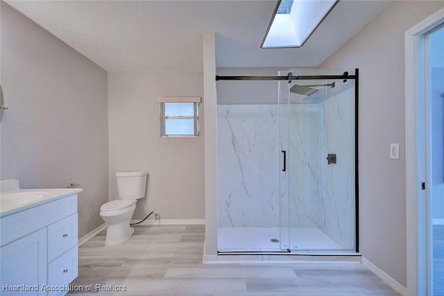 bathroom with toilet, vanity, a marble finish shower, and wood finished floors