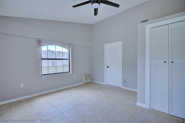 unfurnished bedroom with visible vents, a closet, baseboards, vaulted ceiling, and tile patterned floors