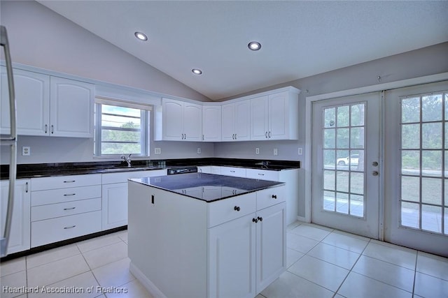 kitchen featuring recessed lighting, light tile patterned floors, a center island, vaulted ceiling, and white cabinetry