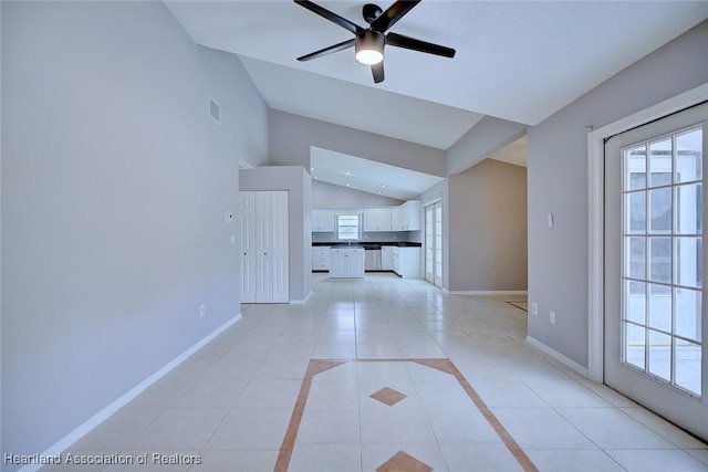 unfurnished living room featuring baseboards, a healthy amount of sunlight, light tile patterned flooring, and lofted ceiling