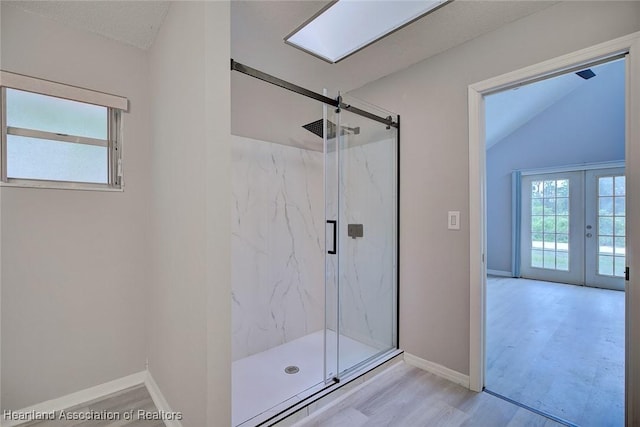 bathroom featuring wood finished floors, a marble finish shower, vaulted ceiling, baseboards, and french doors