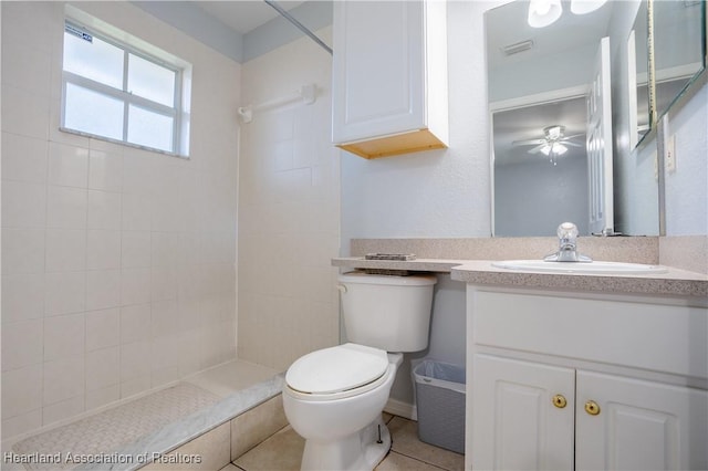 bathroom featuring ceiling fan, tiled shower, vanity, tile patterned floors, and toilet