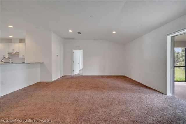 carpeted empty room featuring vaulted ceiling and sink