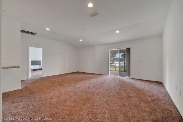 carpeted spare room featuring vaulted ceiling