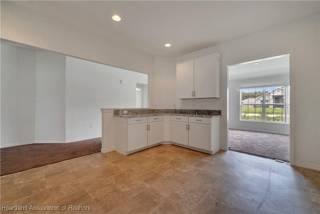 kitchen featuring white cabinets and light carpet