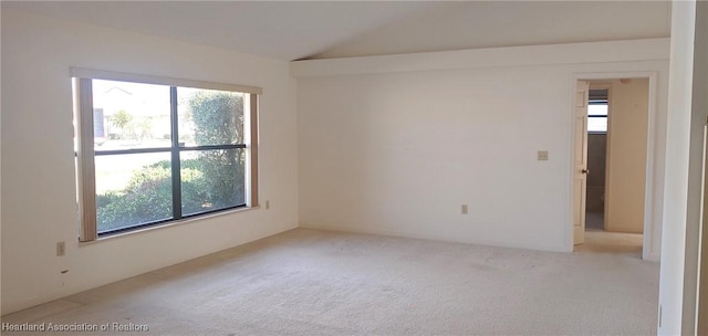 carpeted empty room with vaulted ceiling