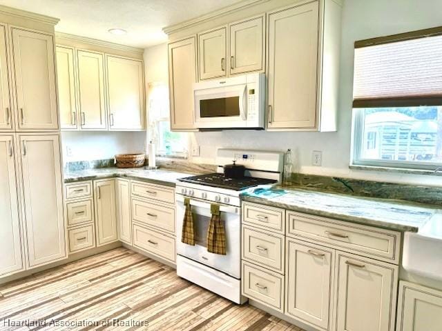 kitchen featuring light stone countertops, white appliances, and cream cabinetry