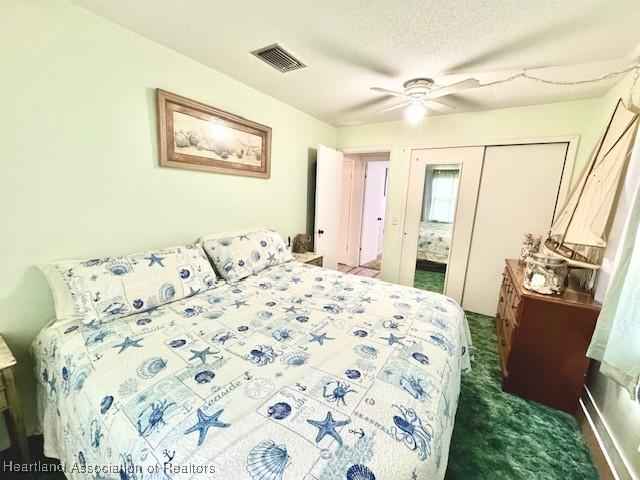 carpeted bedroom with ceiling fan, a closet, and a textured ceiling