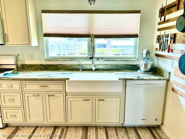 kitchen with range, light stone counters, dishwasher, and sink