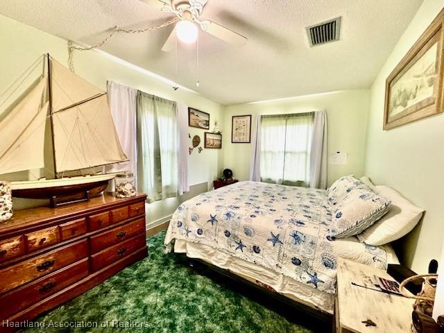 carpeted bedroom with a textured ceiling and ceiling fan