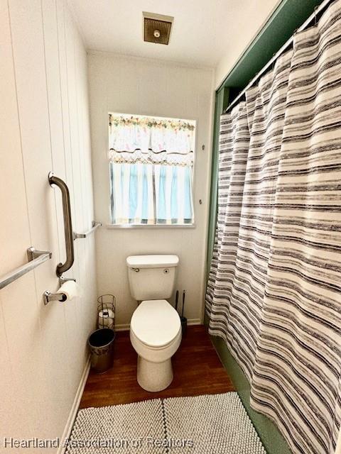 bathroom with hardwood / wood-style floors, toilet, and walk in shower