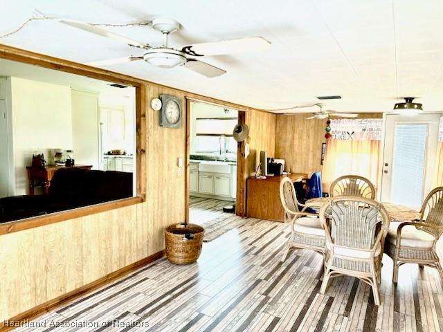 dining space featuring hardwood / wood-style floors, ceiling fan, wood walls, and sink