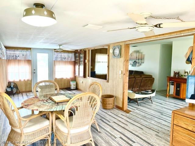 dining room with ceiling fan and wood walls