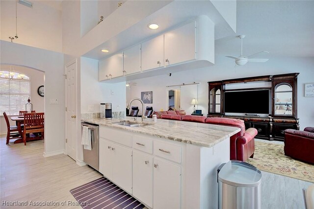 kitchen with stainless steel dishwasher, ceiling fan, sink, high vaulted ceiling, and white cabinetry