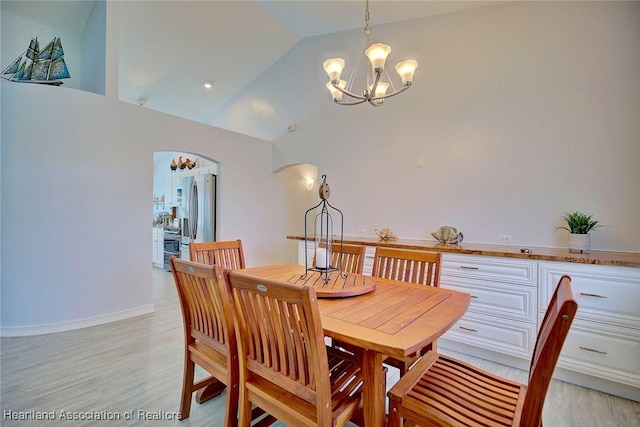 dining room with light hardwood / wood-style flooring, vaulted ceiling, and a notable chandelier