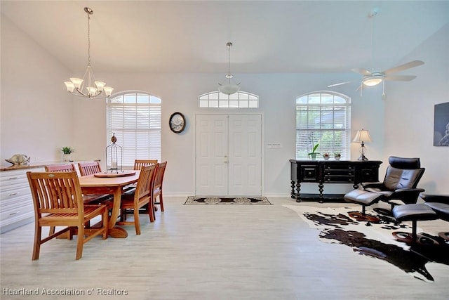 dining room featuring vaulted ceiling, light hardwood / wood-style flooring, a healthy amount of sunlight, and ceiling fan with notable chandelier