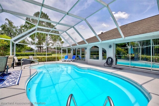 view of pool featuring glass enclosure and a patio area