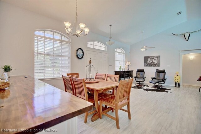 dining area with ceiling fan with notable chandelier, light wood-type flooring, and plenty of natural light