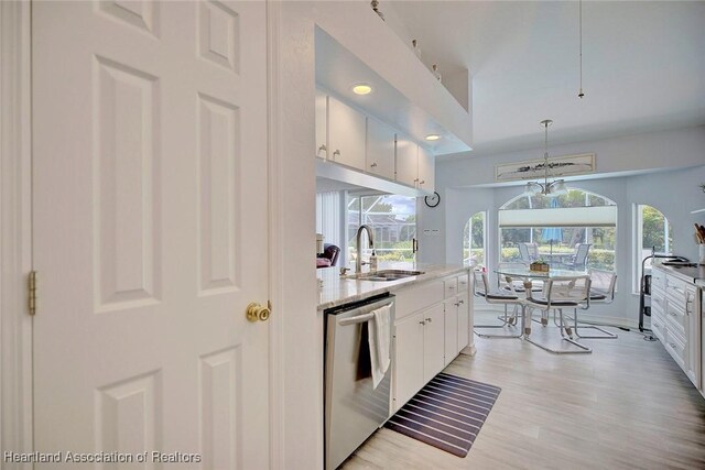 kitchen featuring white cabinets, stainless steel dishwasher, hanging light fixtures, and sink