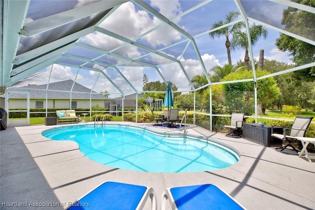 view of swimming pool featuring glass enclosure and a patio