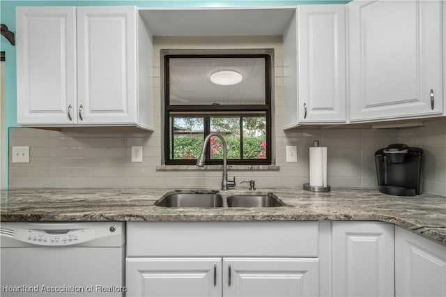 kitchen featuring dishwasher, white cabinets, sink, decorative backsplash, and stone countertops