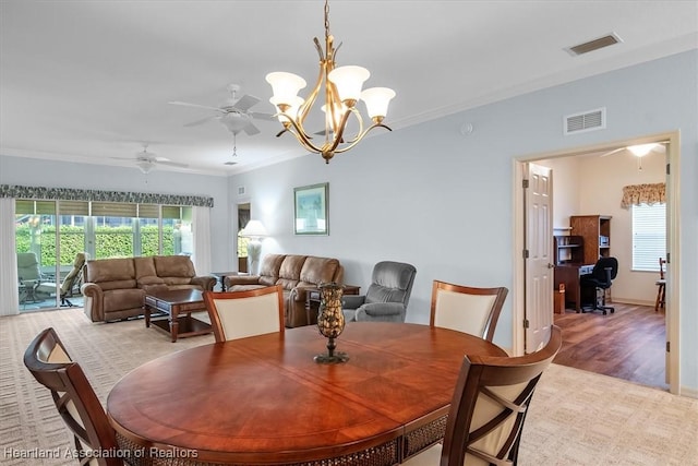 dining space with ornamental molding, ceiling fan with notable chandelier, a wealth of natural light, and light hardwood / wood-style flooring