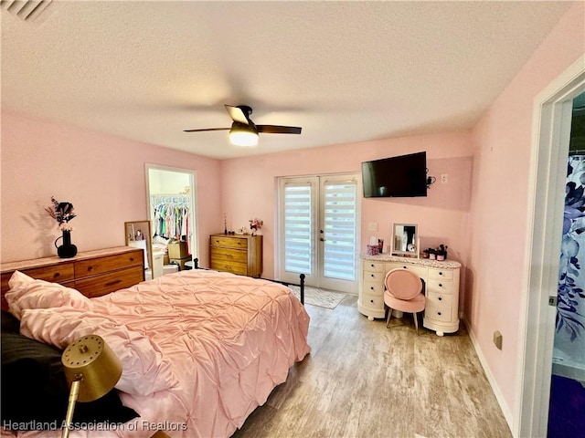 bedroom featuring access to exterior, ceiling fan, light hardwood / wood-style flooring, a walk in closet, and a closet