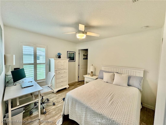 bedroom with ceiling fan, hardwood / wood-style floors, and a textured ceiling