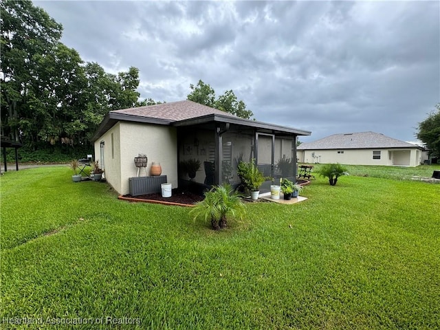 back of property featuring a lawn and a sunroom