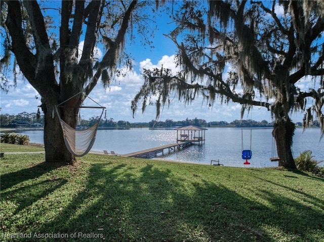 view of dock with a water view and a lawn