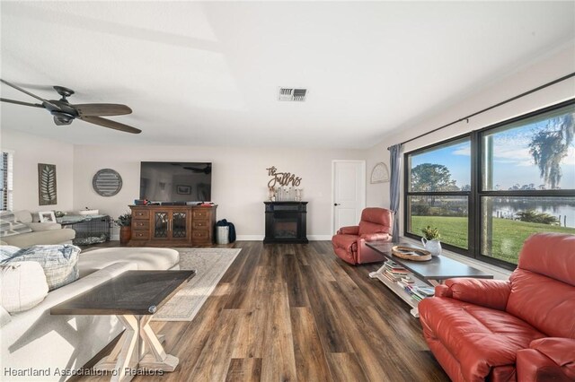 living room featuring a fireplace, wood finished floors, visible vents, and baseboards