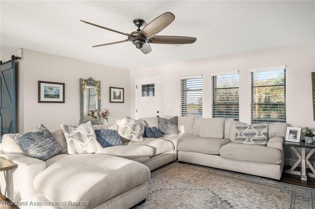 living room featuring a barn door, wood finished floors, and a ceiling fan