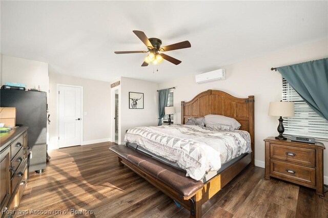 bedroom featuring dark wood-type flooring, freestanding refrigerator, a wall mounted air conditioner, and baseboards