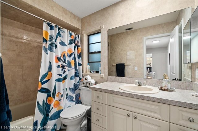 bathroom featuring visible vents, vanity, toilet, and shower / tub combo with curtain