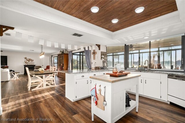 kitchen featuring dark wood-type flooring, wood ceiling, visible vents, a center island, and a raised ceiling