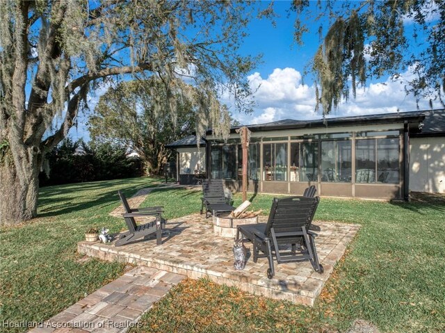 view of yard with an outdoor fire pit, a patio area, and a sunroom