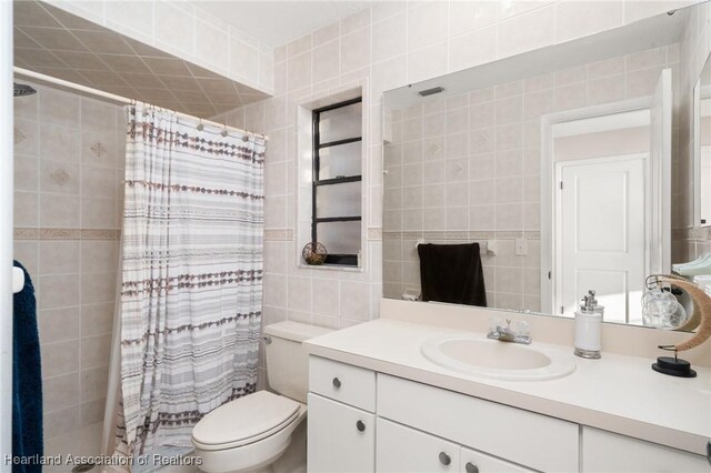 full bathroom with toilet, curtained shower, vanity, and tile walls