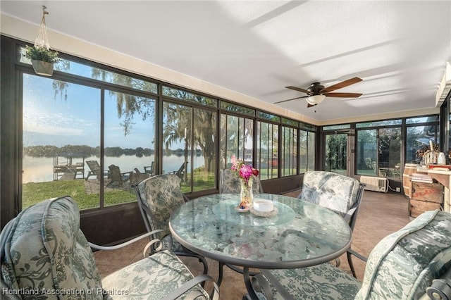 sunroom / solarium with radiator heating unit, a water view, a wealth of natural light, and a ceiling fan