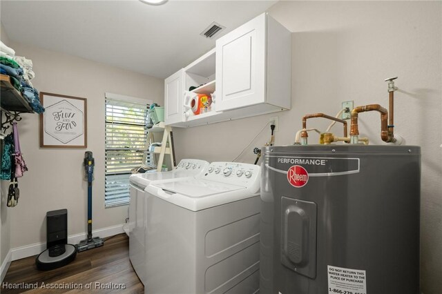 washroom with dark wood-style floors, washer and clothes dryer, cabinet space, electric water heater, and baseboards