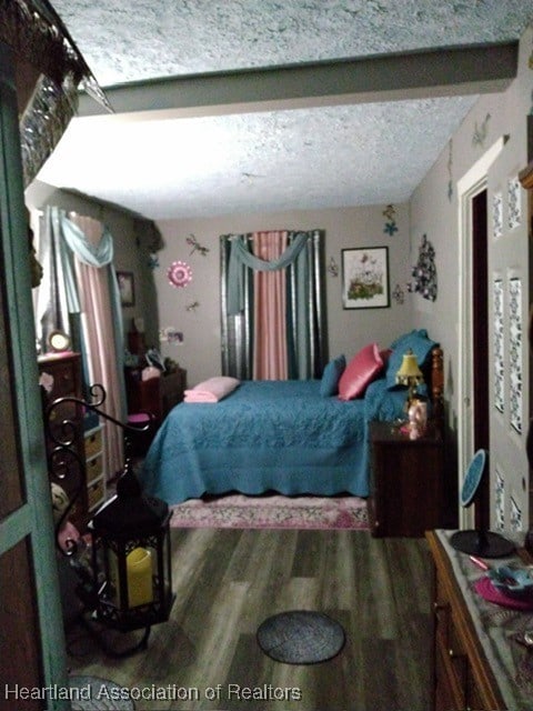 bedroom featuring beam ceiling, wood-type flooring, and a textured ceiling