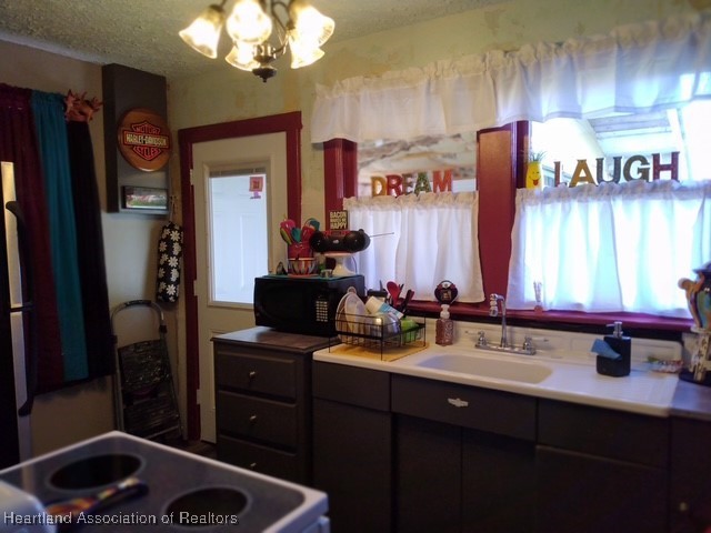 kitchen with a notable chandelier, range with electric cooktop, and sink