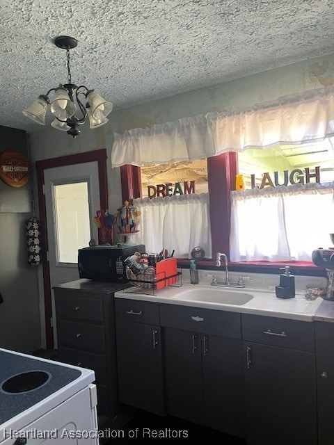 410 Walnut St, Sebring, FL 33870 - kitchen with a chandelier, a sink, a textured ceiling, dark cabinetry, and light countertops