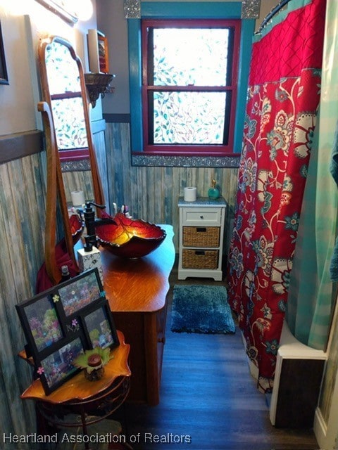 bathroom with shower / bathtub combination with curtain and wood walls