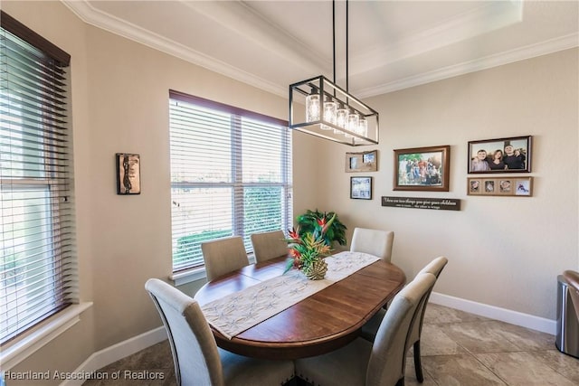 tiled dining area with crown molding and a tray ceiling