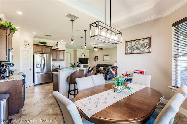 tiled dining space featuring crown molding and ceiling fan