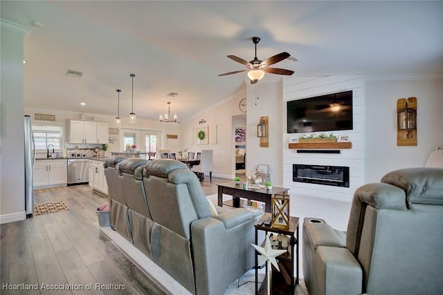 living room featuring sink, a fireplace, ornamental molding, and wood-type flooring