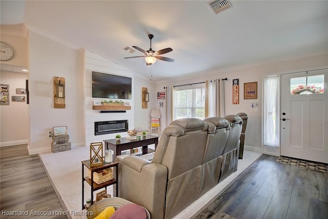 living room with dark hardwood / wood-style floors, a fireplace, vaulted ceiling, and crown molding